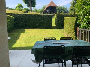 einen Tisch mit vier Stühlen und einem grünen Tischtuch in der Unterkunft Rez-de-jardin - Résidence avec Piscine - Deauville in Deauville