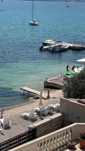 a beach with chairs and boats in the water at Pontus Luxury Apartments in Tivat