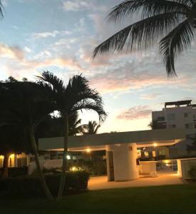 a building with a palm tree in front of a sunset at Villa&Roofgarden -Jacuzzi privado- Relax&Confort in Acapulco
