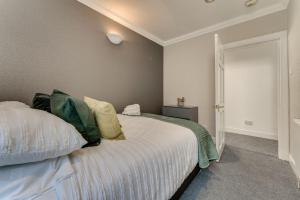 a bedroom with a bed with white sheets and green pillows at The Garden Flat, Loch Lomond in Alexandria