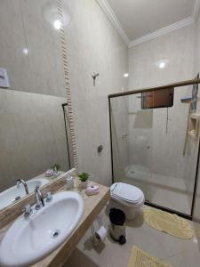a bathroom with a sink and a toilet and a shower at Casa Localizado no Centro de Guape MG in Guapé