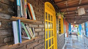 a brick wall with books and a yellow door at Pousada Simbiose in Arraial d'Ajuda