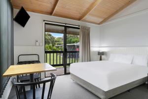 1 dormitorio con cama, escritorio y mesa en The Great Ocean Road Studios, en Port Campbell