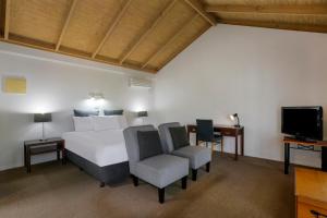 - une chambre avec un lit, deux chaises et une télévision dans l'établissement The Great Ocean Road Studios, à Port Campbell