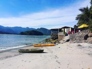 three canoes on a beach next to the water at A VER O MAR FLATS in Caraguatatuba