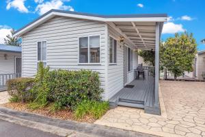 Casa blanca pequeña con terraza de madera en Lifestyle Villages Redhead, en Redhead