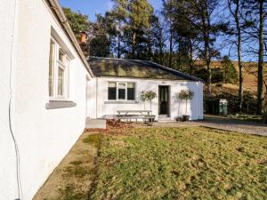 a white house with a picnic table in front of it at White Hillocks Cottage in Inchmill