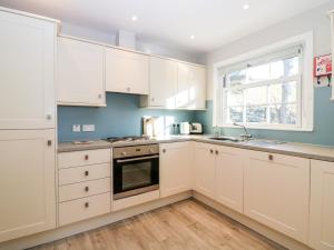 a kitchen with white cabinets and a window at White Hillocks Cottage in Inchmill