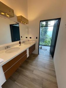 baño con 2 lavabos y ventana grande en Sangregado Lodge en Fortuna