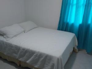 Cette chambre comprend un lit blanc avec des rideaux bleus. dans l'établissement Confort La Española, à Carthagène des Indes