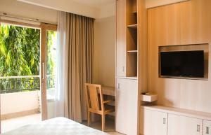 a bedroom with a bed and a television and a balcony at Core Hotel Benoa in Nusa Dua