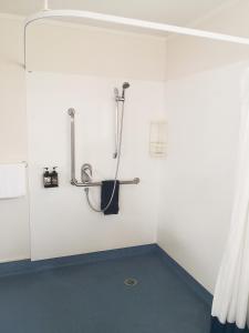y baño con ducha en una pared blanca. en Accommodation at Te Puna Motel, en Tauranga