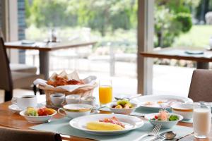 a table topped with plates of food and orange juice at Sapporo Park Hotel in Sapporo