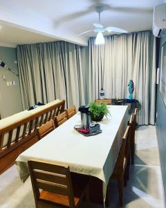uma sala de jantar com mesa, cadeiras e cortinas em RESIDENCIAL MONTE DAS OLIVEIRAS - Arraial D'Ajuda - Porto Seg - Ba - Alto da Pitinga - Casa Premium - Casa Buriti em Porto Seguro