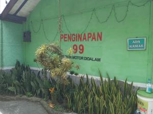 a sign on the side of a building with plants at Penginapan 99 in Bandung