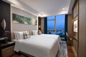 um quarto com uma grande cama branca e uma grande janela em Ascott New District Wuxi em Wuxi