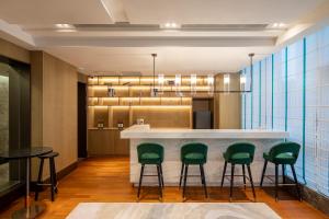 a lobby with a bar with green chairs at Ascott New District Wuxi in Wuxi