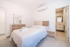 a white bedroom with a large bed and a mirror at Stunning Fuengirola Gem with city and sea views in Fuengirola