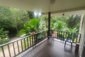 uma varanda de uma casa com duas cadeiras e árvores em Private Rainforest Ridge Retreat em Kuranda