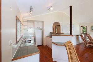 - une cuisine avec des placards blancs, une table et des chaises dans l'établissement Private Rainforest Ridge Retreat, à Kuranda