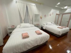 2 camas en un dormitorio con paredes blancas y suelo de madera en minimal house phichit, en Phichit