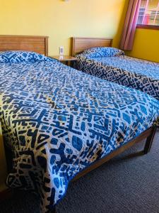 a bedroom with two beds with a blue and white bedspread at Hospedaje in Osorno