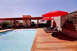 a pool with red umbrellas and chairs and a swimming pool at Residence ACQUA LINDA Porticcio in Porticcio