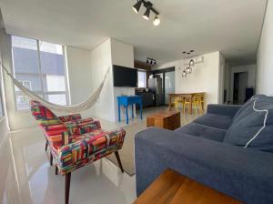 a living room with a blue couch and a chair at Ed. Mauí, 2 suítes, divisa Capão e Atlântida in Capão da Canoa