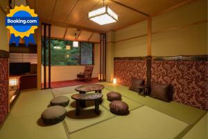 een woonkamer met een tafel en een aantal poeven bij Ryokan Gizan in Takayama