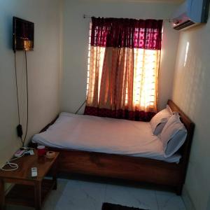 a bedroom with a bed with a window and a table at Hotel Bonolota international in Rājshāhi