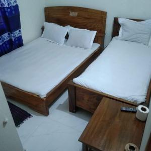 two twin beds in a room with a table at Hotel Bonolota international in Rājshāhi