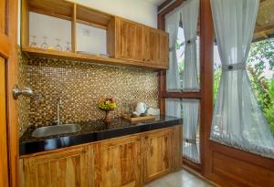 a kitchen with wooden cabinets and a sink at Pangkung Carik Villa by Pramana Villas in Blahbatu