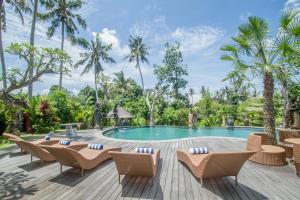 a pool at a resort with chairs and trees at Pangkung Carik Villa by Pramana Villas in Blahbatu