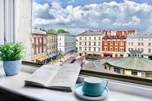 an open book on a window sill with a cup and a coffee mug at GREEN APARTMENTS #Nowy Square, Kazimierz district in Kraków
