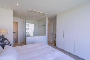 a bedroom with a white bed and a mirror at Unit 215 Oceandune - Stunning & Modern Apartment in Sibaya