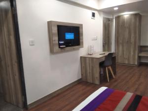 een kamer met een bureau en een tv aan de muur bij HOTEL INDUS INN in Pune