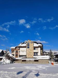 un bâtiment avec de la neige devant lui dans l'établissement Hotel FAMIL - adults only, à Bansko