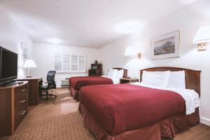 Sky-Palace Inn & Suites McCook في ماكوك: غرفة فندقية بسريرين وتلفزيون بشاشة مسطحة