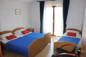 um quarto com 2 camas com almofadas azuis e vermelhas em Guesthouse San Antonio em Ploče
