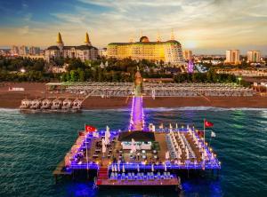 ein Pier im Wasser mit einem Resort im Hintergrund in der Unterkunft Delphin Imperial Lara in Lara