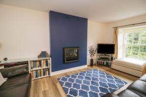 a living room with a couch and a blue wall at Derwentwater Apartment in Keswick