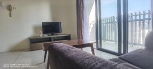 a living room with a couch and a television at Pool view + water theme park @swiss garden residence in Kuantan