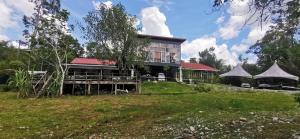 uma casa com um telhado vermelho num campo verde em Badul Homestay em Musi