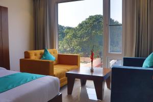 a bedroom with a bed and a chair and a window at Green Hotel in Rishīkesh