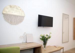 uma sala de estar com televisão e um vaso de flores em Pansion Legrađanka em Legrad