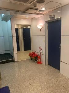 um corredor de um edifício de escritórios com duas portas e flores em City Hotel Dolphin em Tóquio