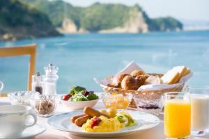 een tafel met ontbijtproducten en uitzicht op de oceaan bij Nichinankaigan Nango Prince Hotel in Nichinan