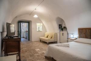 ファザーノにあるMasseria Trotta B&Bのベッドルーム(ベッド1台、テレビ、椅子付)