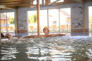 un hombre tendido en un jacuzzi en una piscina en Drevernos kempingas en Dreverna