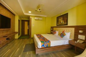 a bedroom with a bed and a flat screen tv at FabHotel Phoenix Resorts in Bangalore